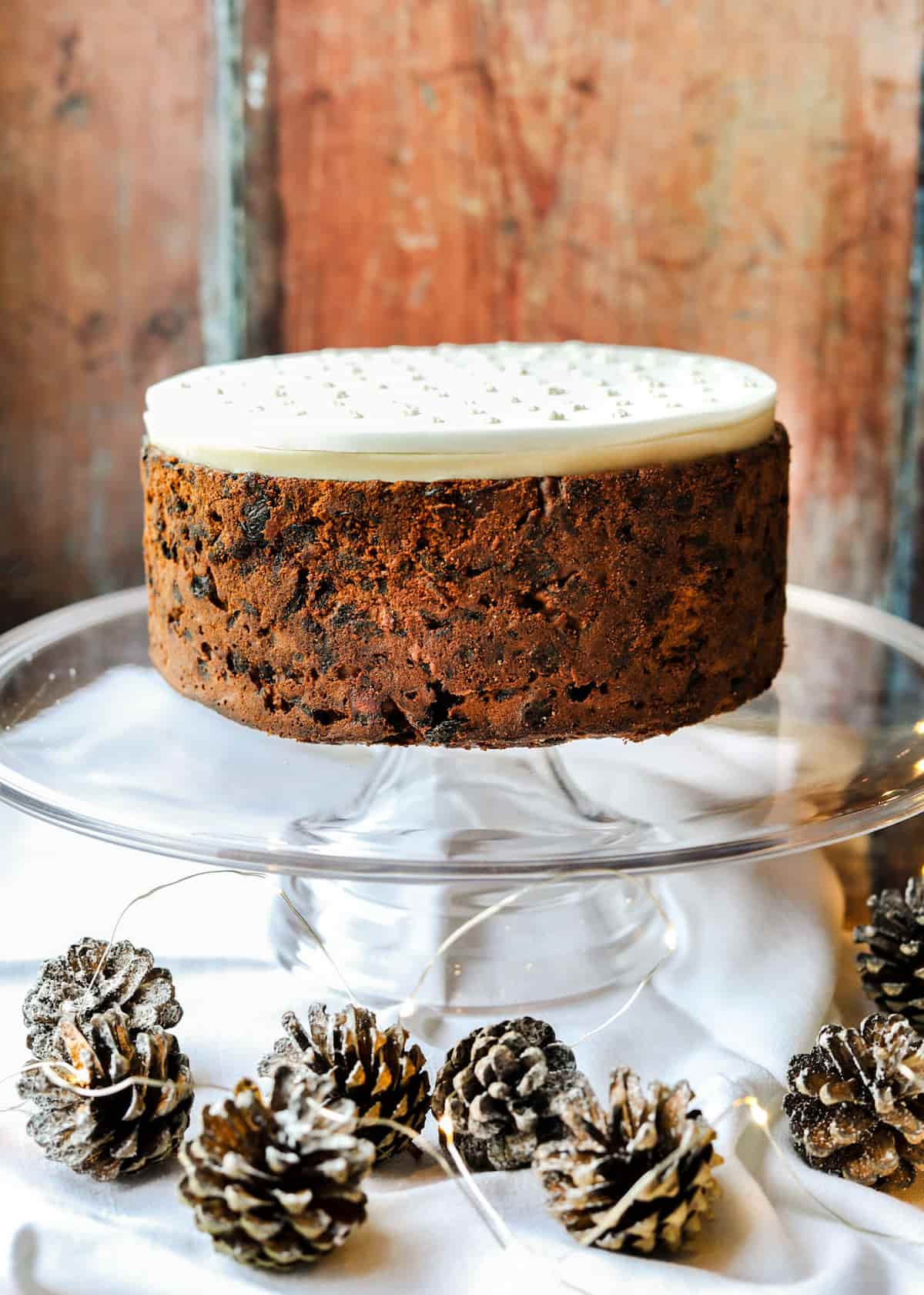 Paul Hollywood's Christmas Cake on stand with pine cones