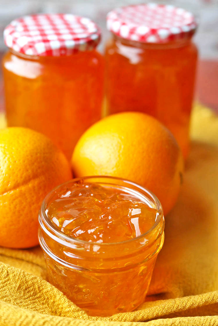 jars of seville orange marmalade with oranges and open jar.
