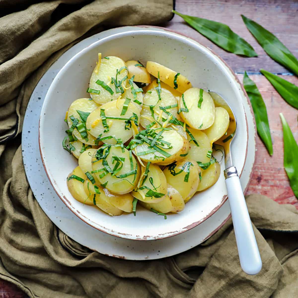 New potatoes with wild garlic & lemon in bowl with spoon
