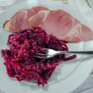 White plate with slice of ham and red cabbage with ginger preserve, also fork.