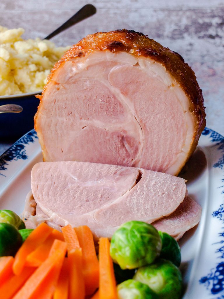 Slices of Slow Cooker Ham in Ginger Beer with vegetables.