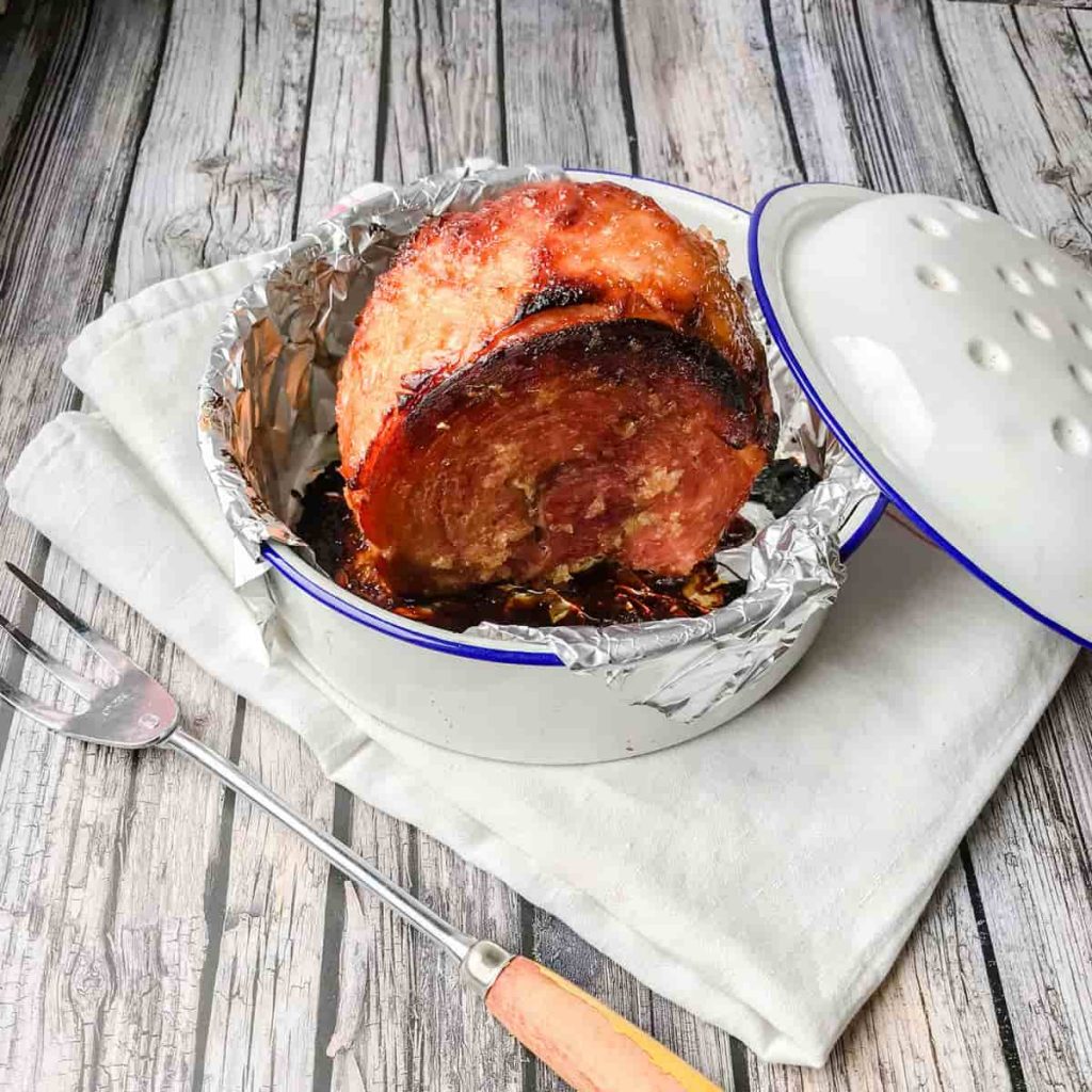 Ham in roasting tin with carving fork.