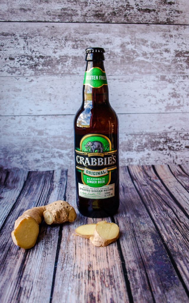Bottle of Crabbies Alcoholic Ginger Beer and fresh root ginger.