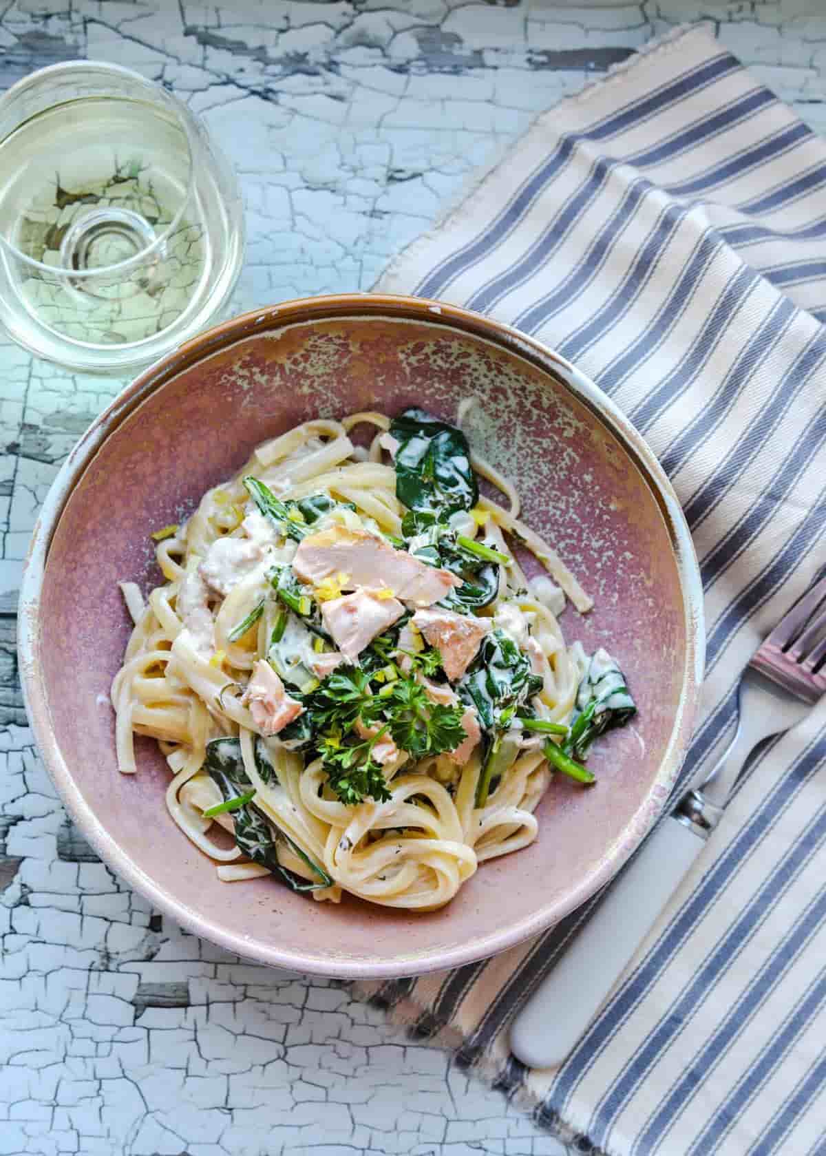Creamy Trout and Spinach Pasta on striped cloth with fork and glass