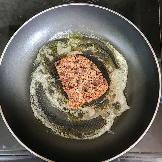 Slice of fruit pudding cake frying in butter in a pan