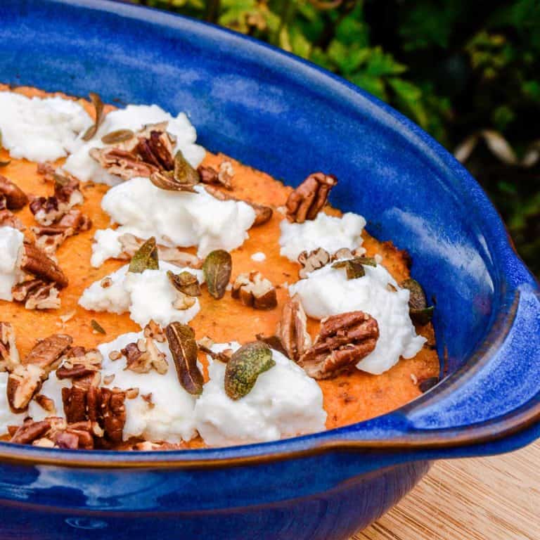 Blue serving dish of Sweet Potato Mash with ricotta, sage and pecan nuts.