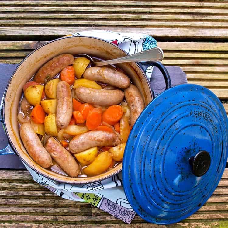 cider, apple and sausage casserole with lid on side of casserole.