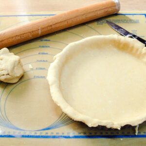 pastry lined tart tin, ball of pastry dough and rolling pin.