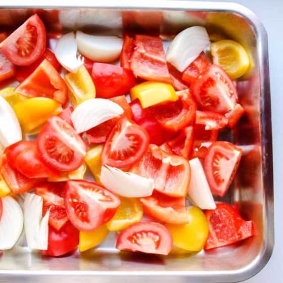 Peppers, tomatoes and onion wedges in roasting tin for Roast Pepper & Tomato Coucous