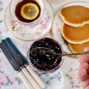Blackberry and Apple Jelly on a spoon with pancakes and a cup of tea