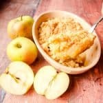 Classic Apple Crumble in baking dish with spoonful of cooked crumble and apples