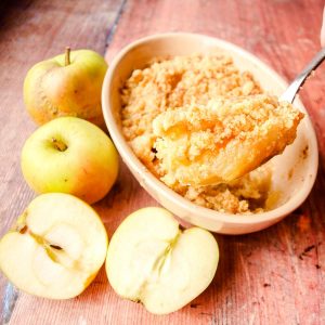 Classic Apple Crumble in baking dish with spoonful of cooked crumble and apples