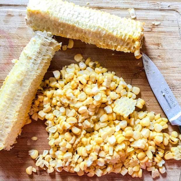 corn kernels and two empty corn cobs with knife.