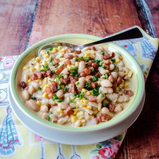 Bowl of corn succotash with spoon in it