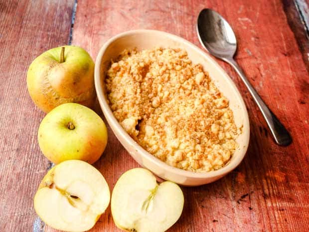 Bowl of Baked apple dessert with spoon and apples 