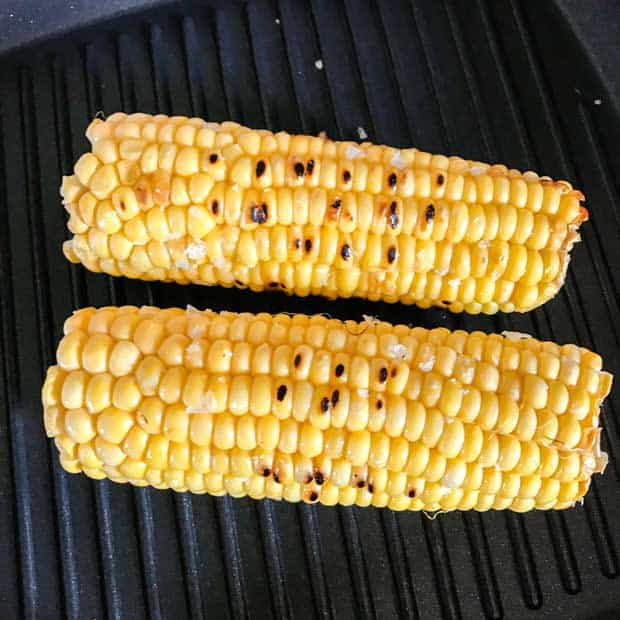 Two grilled Corn Cobs on a griddle pan