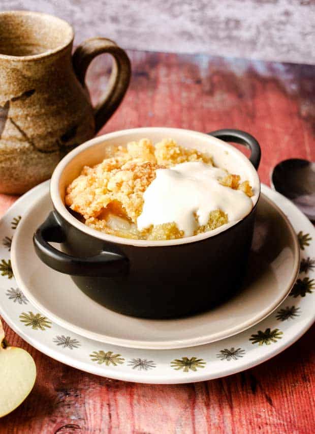 Bowl of apple crumble with custard, jug in background