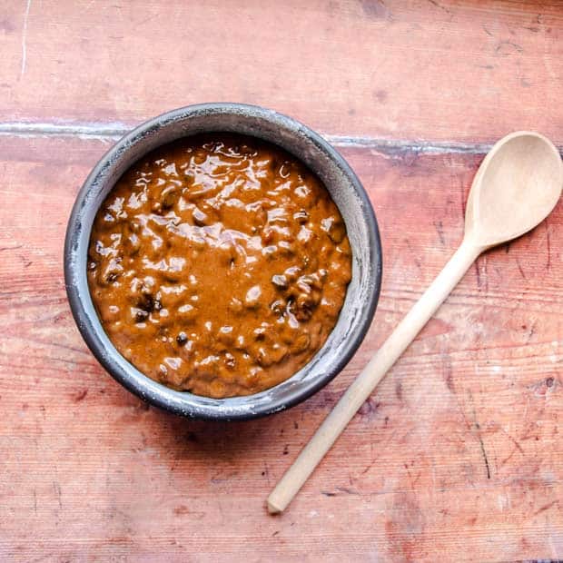 Puddng basin filled with fruit pudding mixture and wooden spoon