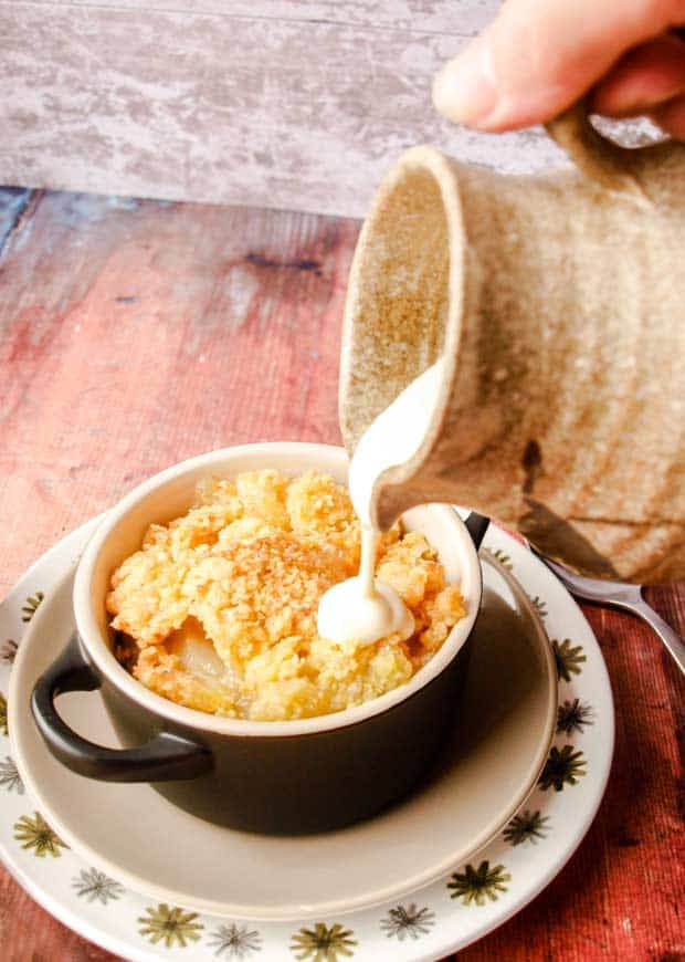 pouring easy vanilla custard sauce onto apple crumble 