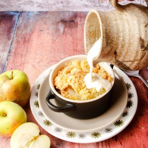 pouring custard onto bowl of crumble