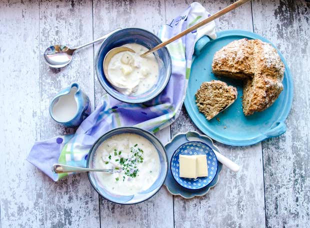 Two bolws of Cullen Skink Soup with bread on a platter, butter plate and a jug of cream.