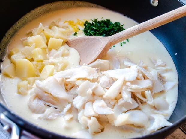 Pan with creamy Cullen Skink soup, smoked haddock flakes, cubes of potato and parsley, wooden spoon 