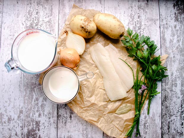 potatoes, onion, parsley, chives, and smoked haddock on paper. Jugs of milk and cream beside for Scottish Cullen SKink