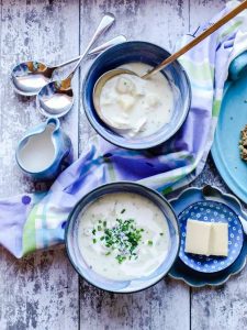 Two bowls of Scottish Cullen Skink with spoons, butter and cream in jug