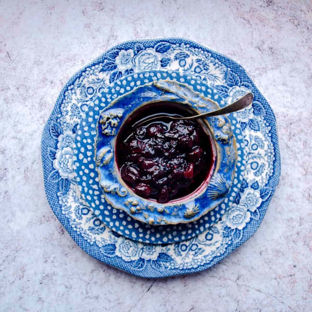 Bowl on Easy Cranberry & Red Wine Sauce with spoon on plate. 