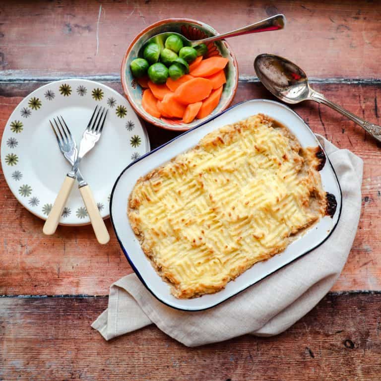 Potato topped Leftover Turkey Shepherd's Pie, plate with forks and bowl of vegetables