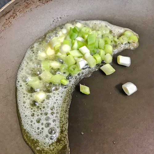 Seafood pancakes spring onions cooking in pan