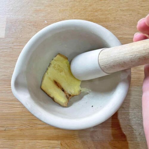 fresh root ginger in mortar with pestle