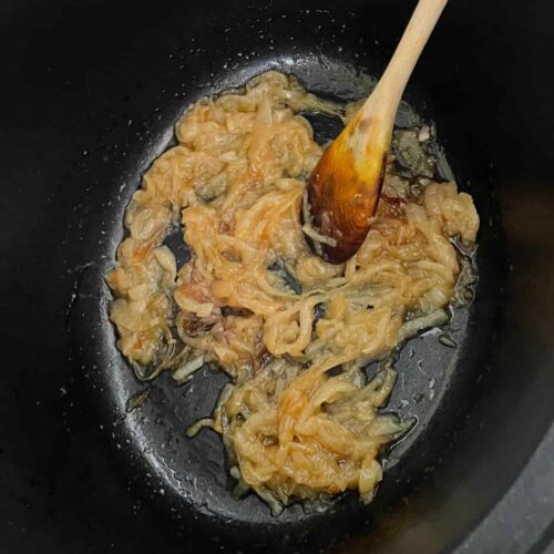 French onion soup caramelised onions with wooden spoon