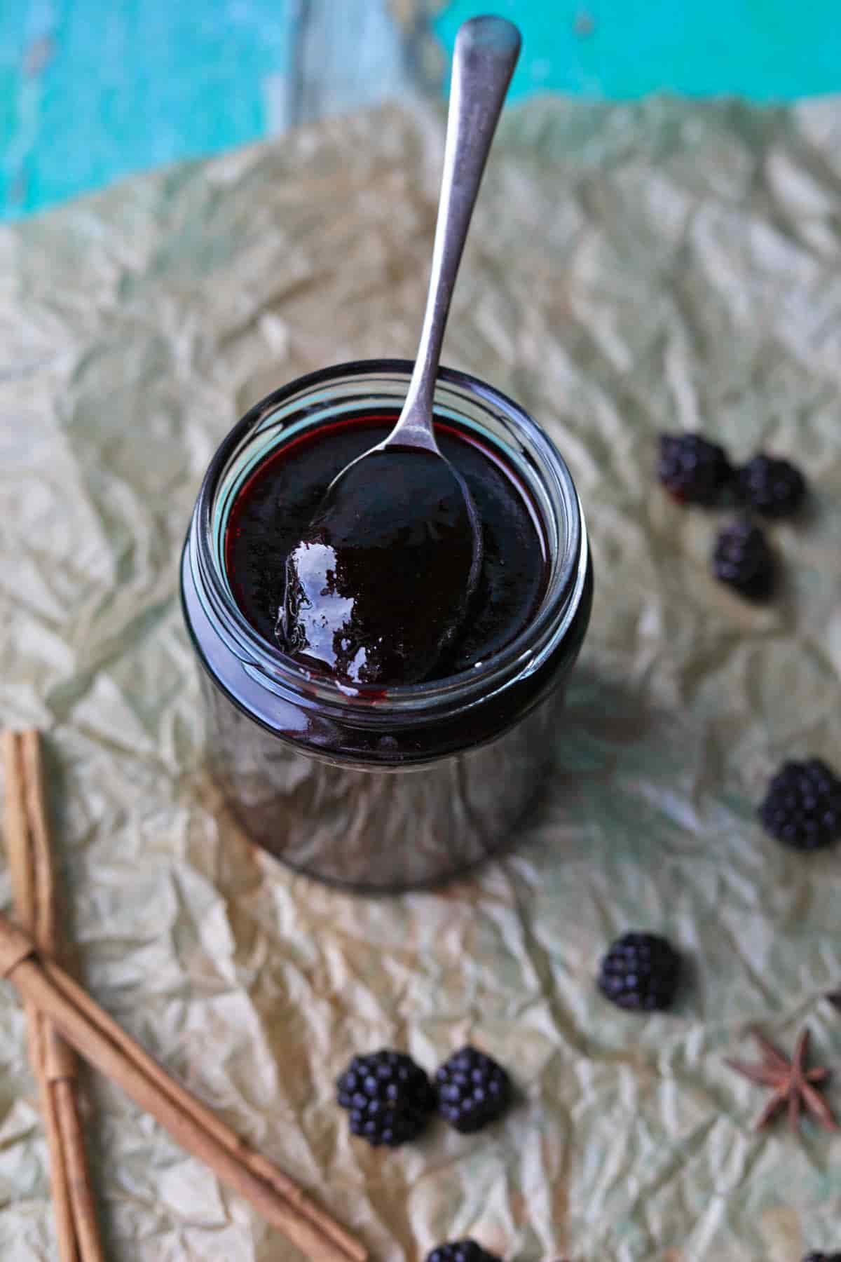 Spiced Blackberry Jam in jar with spoon and blackberries