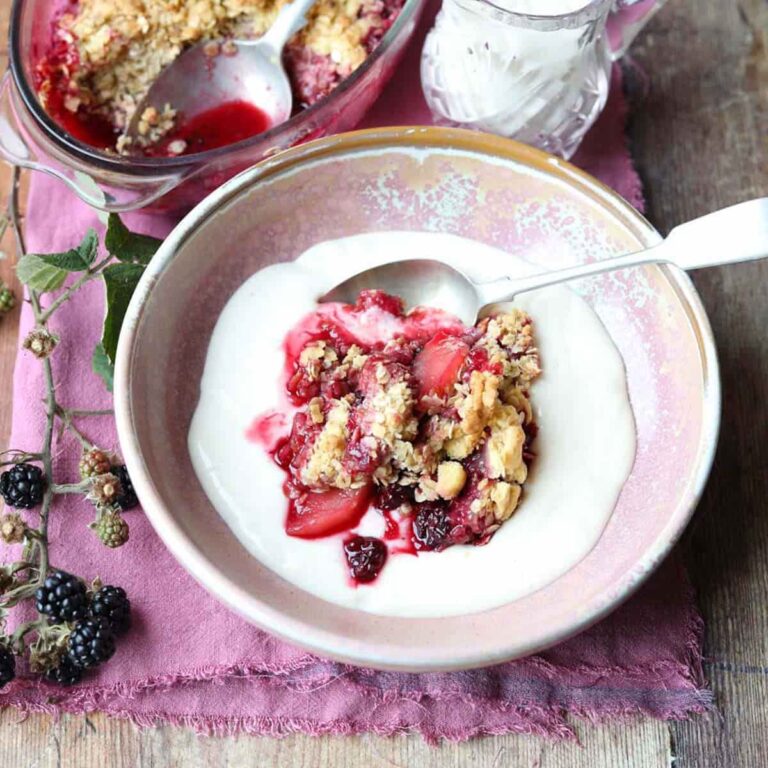 Blackberry and Applle Crumble in bowl with serving dish and spoons