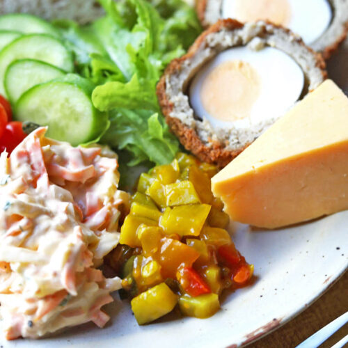 courgette relish on plate with salad, cheese and scotch egg.