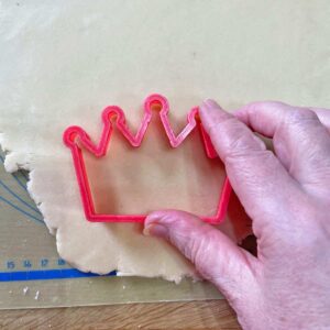 Coronation cookie dough with crown cutter and hand