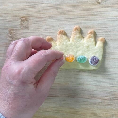 Coronation Cookies Shortbread Crowns with hand placing sweets on cookies