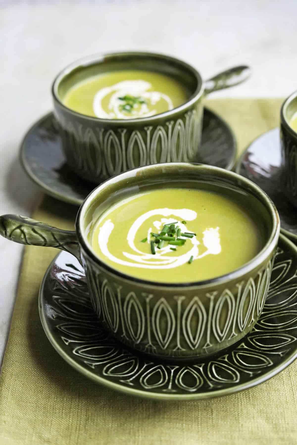 bowls of lettuce soup with spoons