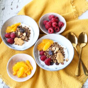 two bowls of gingerbread granola with oranges and raspberries