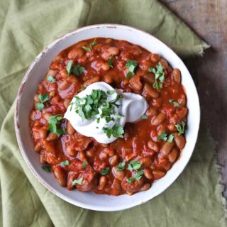 Slow Cooker Baked Beans with Chorizo in bowl with sour cream