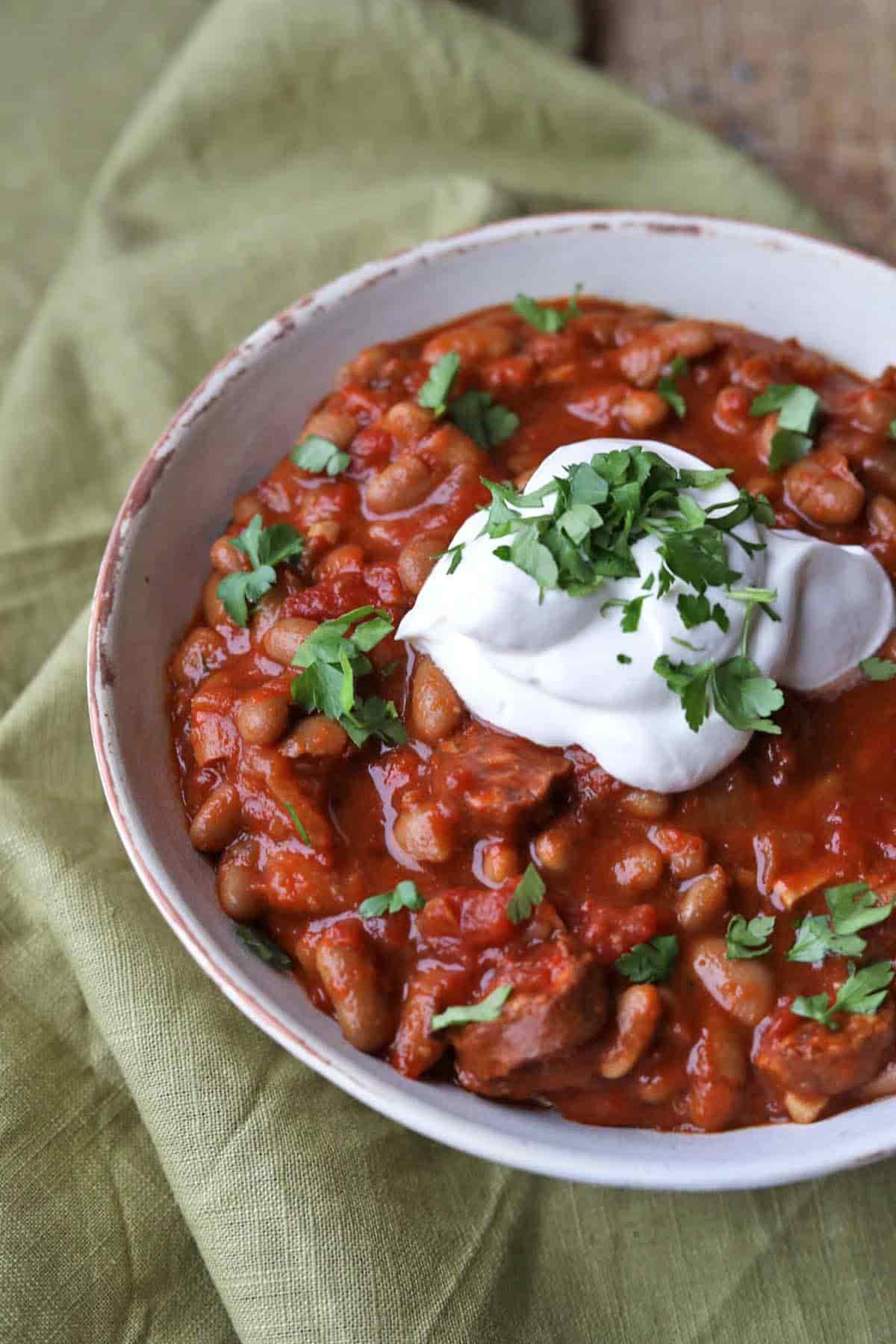 Slow Cooker Baked BEans with Chorizo in bowl with sour cream