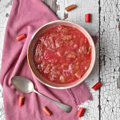 rhubarb compote in bowl with spoon and pieces of rhubarb.