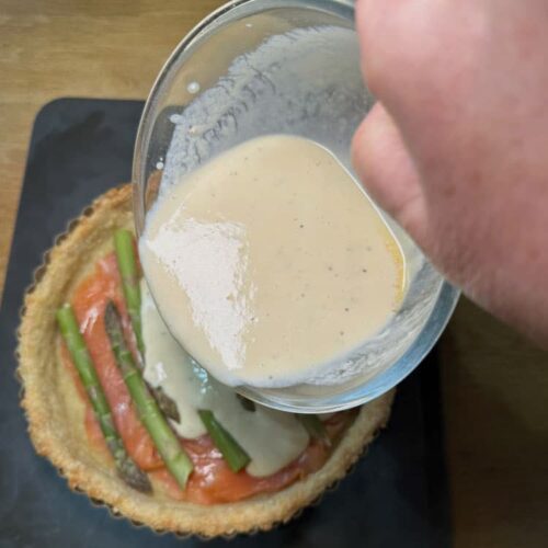 pastry case with bowl of egg and cream poured onto filling.