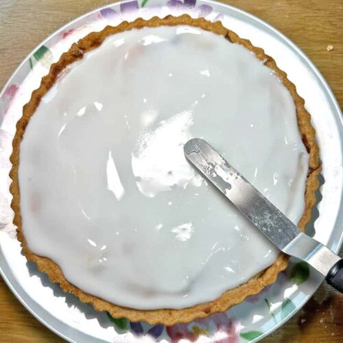 spread icing over cherry and almond frangipane tart.