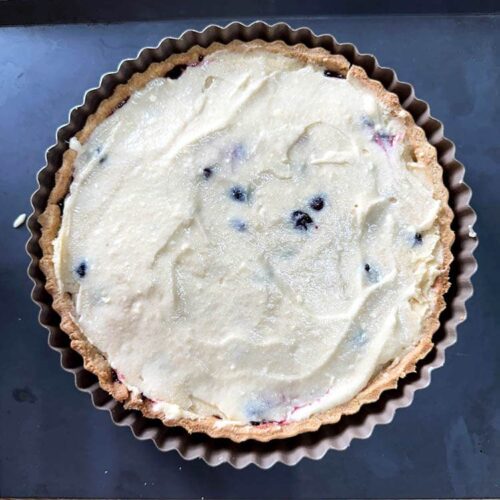 spread frangipane over cherries on cherry and almond frangipane tart.