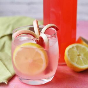 rhubarb and ginger cordial in glass with ice and lemon.