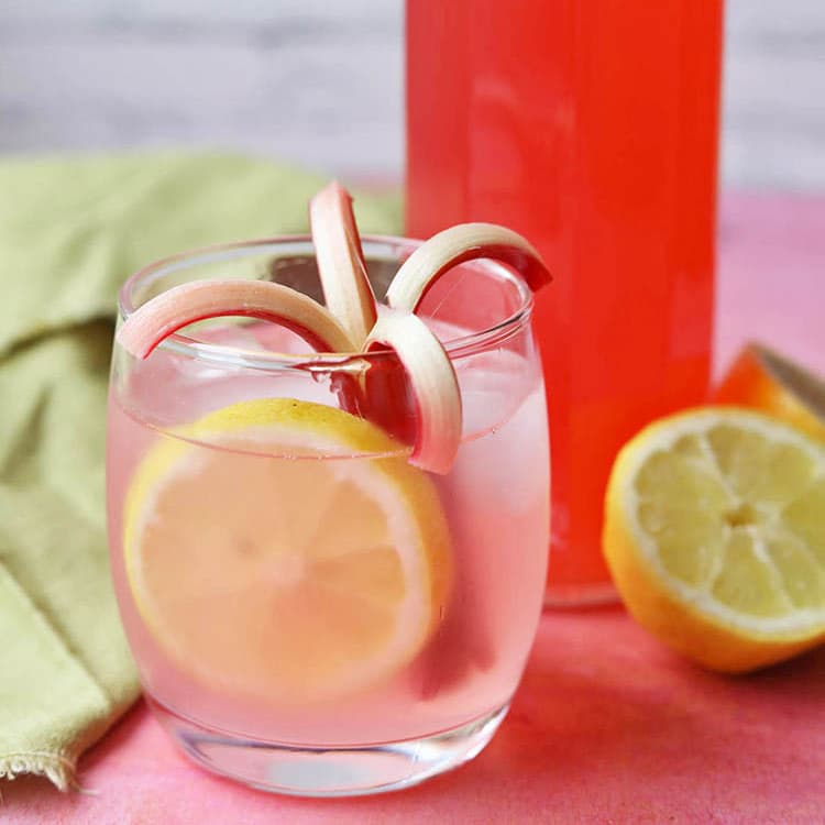rhubarb and ginger cordial in glass with ice and lemon.