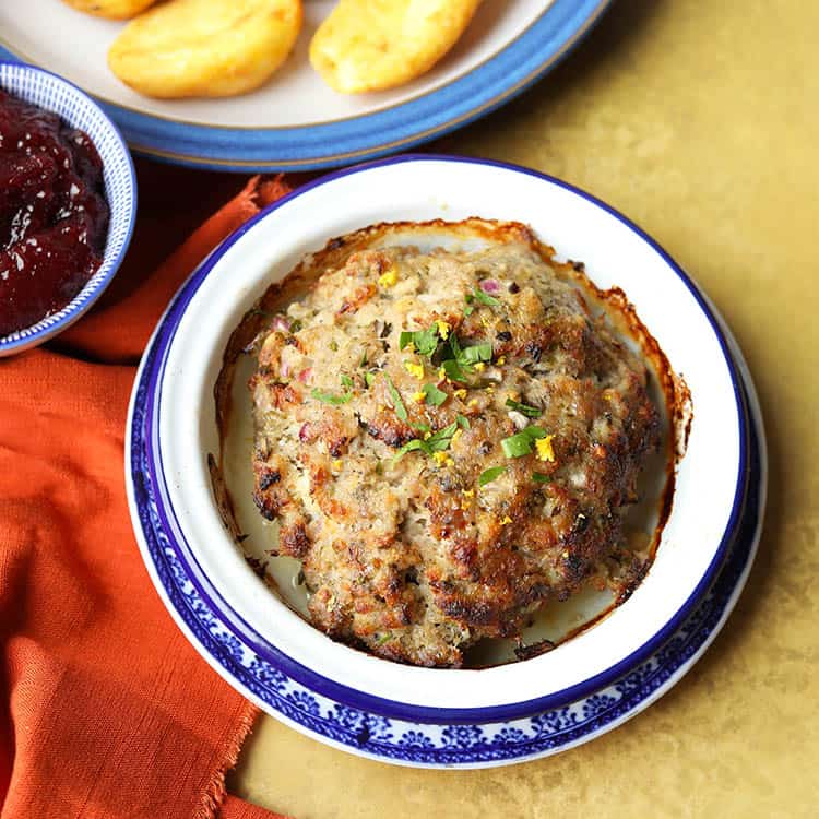 lemon and herb sausagemeat stuffing in bowl with roast potatoes.