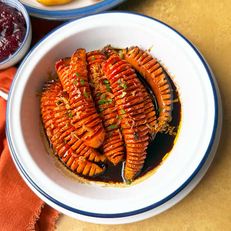 hasselback carrots in bowl with brown sugar glaze.